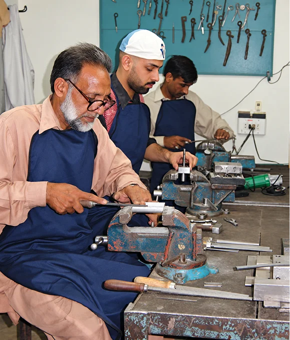 Craftsmen hand-finishing surgical instruments at the workbench