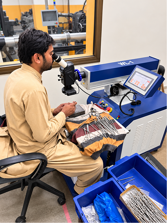 Technician laser-welding surgical instruments under magnification