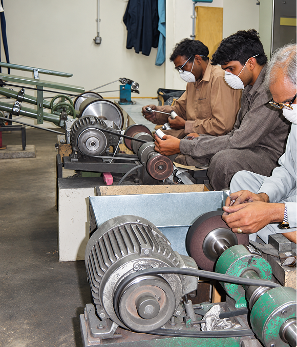 Workers grinding and polishing surgical instruments